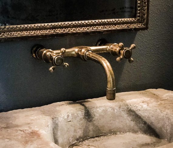 Powder bath with an antique vessel sink and mirror. Wall mounted unlacquered brass faucet.