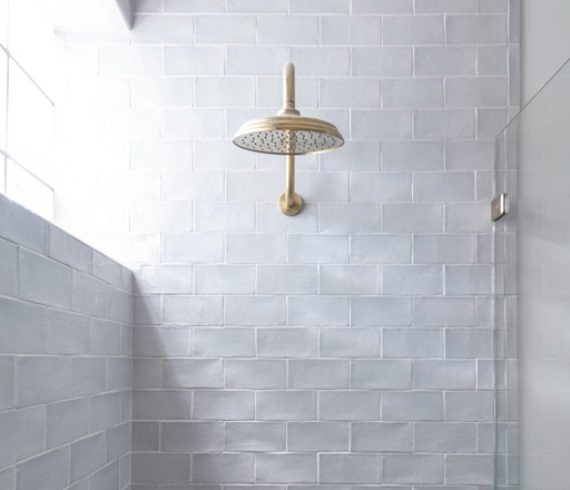 Pool bath shower with subtle texture and unlacquered brass fixtures. Photographed by Michael Hunter.
